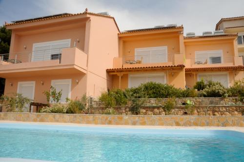 a villa with a swimming pool in front of a house at Aegean View Villa in Loutraki