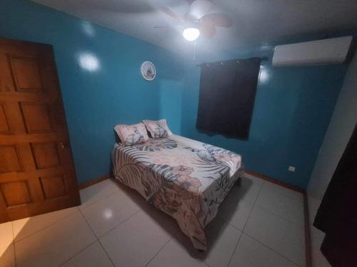 a small bed in a room with a blue wall at Maina Lodge in Avatoru