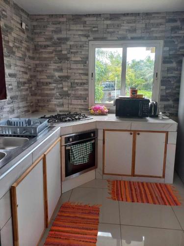 a kitchen with a stove and a sink and a window at Maina Lodge in Avatoru