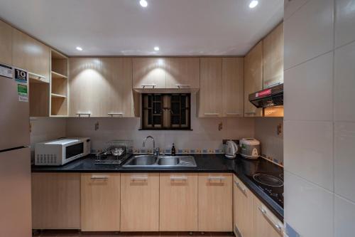 a kitchen with wooden cabinets and a sink and a microwave at Sherwood Residence in Ho Chi Minh City