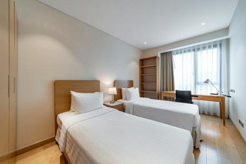 a hotel room with two beds and a desk at Sherwood Residence in Ho Chi Minh City