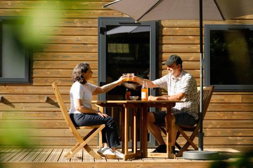 a man and woman sitting at a table with drinks at FORET TOTEM - Hébergements nature et bien-être en pleine forêt in Persquen