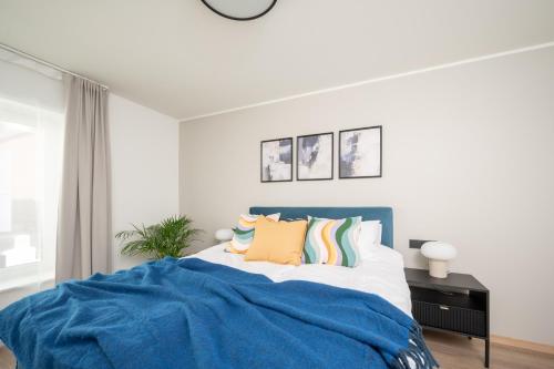 a white bedroom with a blue bed with pillows at Pärnu Pearl Residences in Pärnu