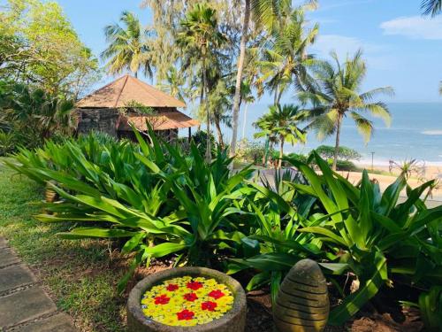 a garden with flowers in front of a beach at Niraamaya Wellness Retreats, Surya Samudra, Kovalam in Kovalam