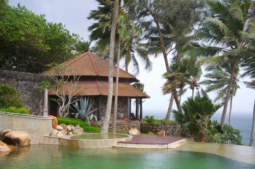 a house with a swimming pool next to a resort at Niraamaya Wellness Retreats, Surya Samudra, Kovalam in Kovalam