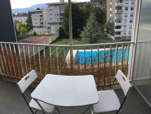 une table blanche et des chaises sur un balcon avec vue dans l'établissement Studio PLEUMEUR, à Chambéry
