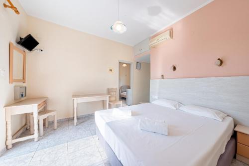 a bedroom with a large white bed and two tables at Alex bar apartments in Sarakiniko