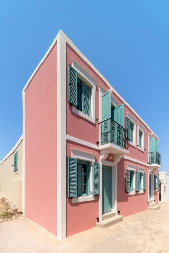 a pink building with green shutters at Via Vasileia in Kattavía