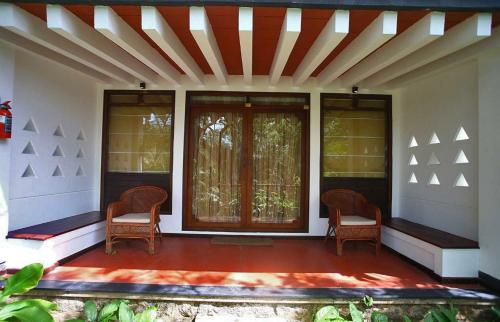 a porch of a house with two chairs and windows at Niraamaya Wellness Retreats, Surya Samudra, Kovalam in Kovalam