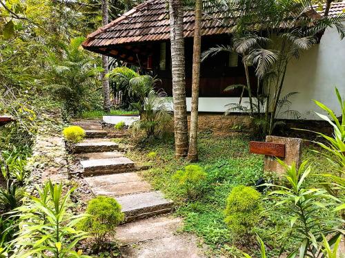 a garden with a path leading to a house at Niraamaya Wellness Retreats, Surya Samudra, Kovalam in Kovalam