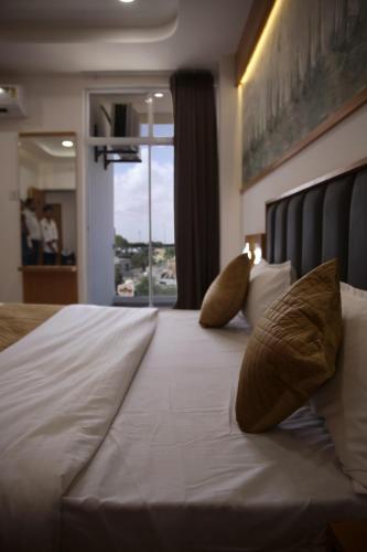 ドワルカにあるHotel The Grand Shivaの大きな白いベッド(枕2つ付)、窓が備わります。