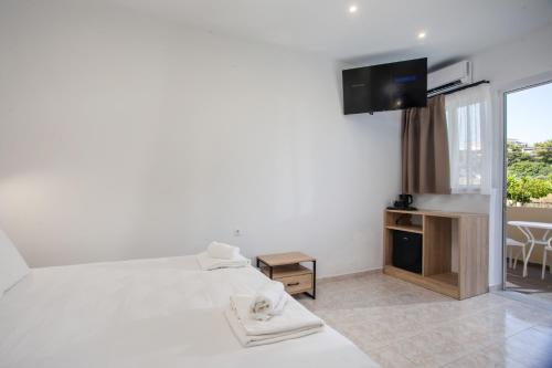 a bedroom with a bed and a tv and a window at Olevia Comfort in Faliraki