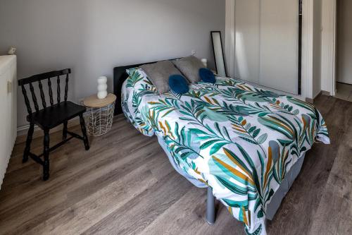 a bedroom with a bed with a colorful comforter and a chair at Appartement paisible au bord de l Isle avec parking in Périgueux