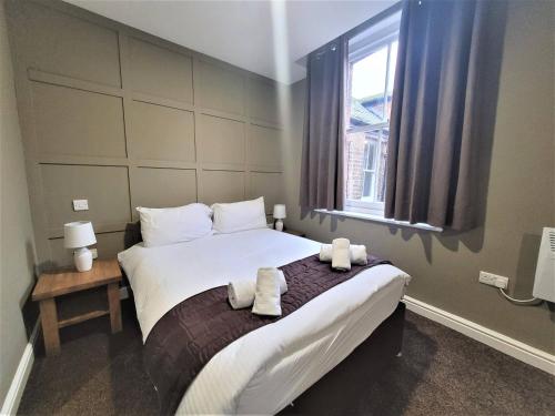 a bedroom with a large bed with towels on it at New County Hotel & Serviced Apartments by RoomsBooked in Gloucester