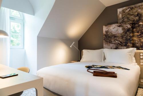 a bedroom with a white bed and a desk at Dolce by Wyndham Versailles - Domaine du Montcel in Jouy-en-Josas