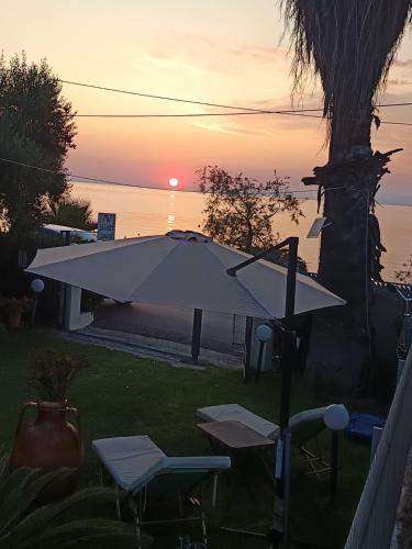 a sunset over the water with a table and chairs at Sunset Oasis in Roitika