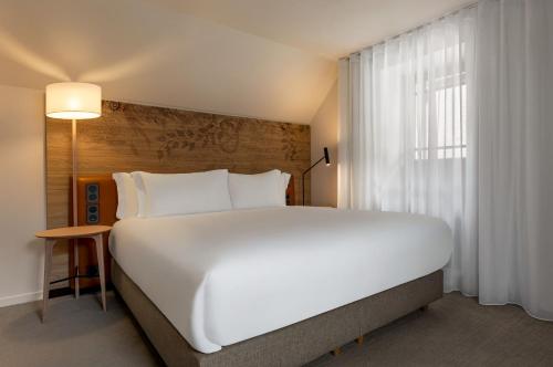 a large white bed in a room with a window at Dolce by Wyndham Versailles - Domaine du Montcel in Jouy-en-Josas