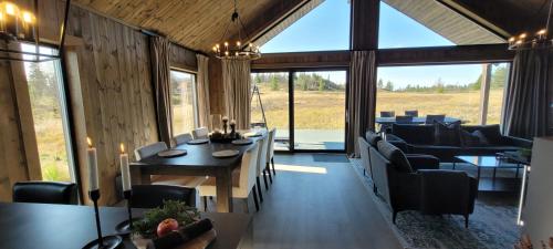 Un comedor con mesa y sillas y ventanas. en Luxury Mountain Cabin Modern and Stylish, en Uppheim