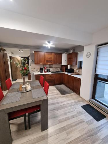 a large kitchen with a table and red chairs at Apartament Kalinderu K2 Busteni in Buşteni