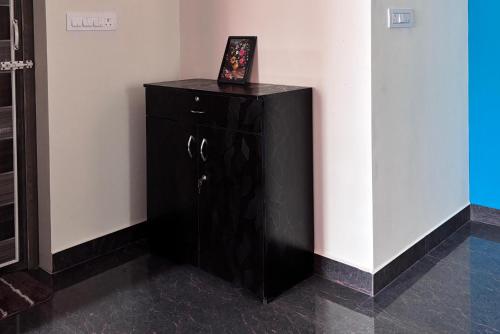 a black cabinet in a corner with a picture on it at Samuels Comfort Homes in Bengaluru