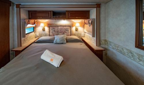 a large bed in a small room with two windows at ATHENS MOTORHOME park RV WINNEBAGO in Pallíni