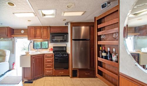 a kitchen with wooden cabinets and a stainless steel refrigerator at ATHENS MOTORHOME park RV WINNEBAGO in Pallíni