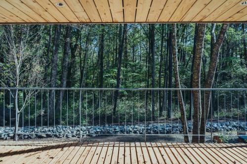 a wooden deck with a view of a forest at SANU 2nd Home 八ヶ岳 3rd in Nagasawa