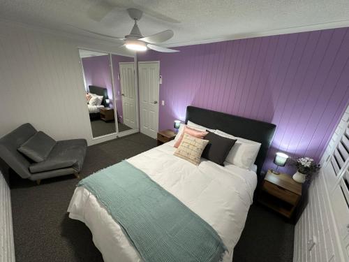 a bedroom with a bed and a purple wall at Central Cullen Wagga Apartments in Wagga Wagga