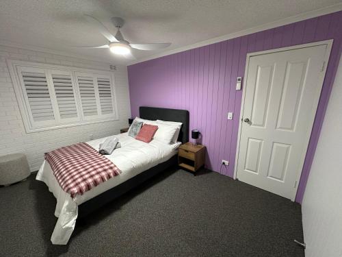 a bedroom with a bed with a purple wall at Central Cullen Wagga Apartments in Wagga Wagga
