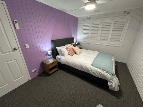a bedroom with purple walls and a bed with a night stand at Central Cullen Wagga Apartments in Wagga Wagga