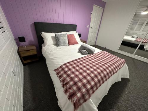a bedroom with a large bed with a plaid blanket at Central Cullen Wagga Apartments in Wagga Wagga