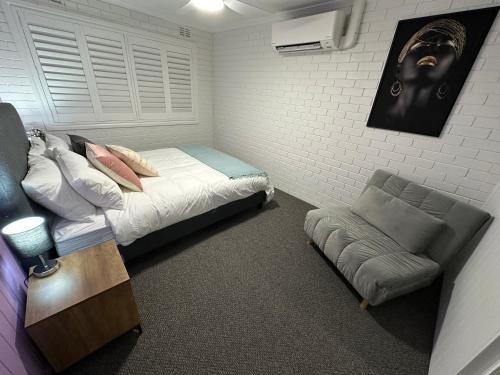 a bedroom with a bed and a couch and a chair at Central Cullen Wagga Apartments in Wagga Wagga
