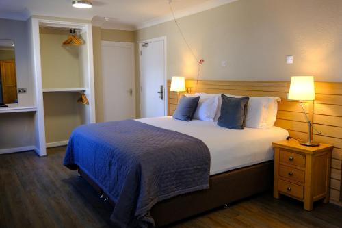 a bedroom with a large bed with blue and white pillows at Glen Mhor Hotel at Uile-bheist 'Brewstillery' in Inverness