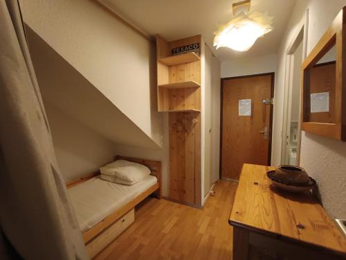 Cette petite chambre comprend un lit et une table en bois. dans l'établissement Studio rénové avec coin montagne, balcon, parking privé et animaux acceptés - FR-1-445-62, à Montgenèvre