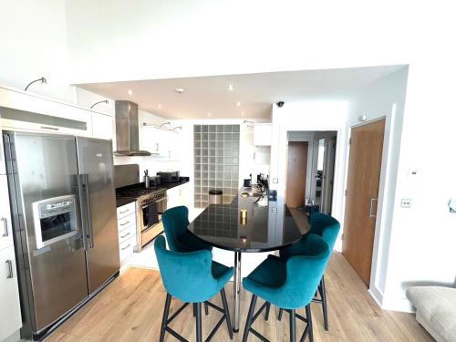 a kitchen with a black table and blue chairs at Seaview Hideway - Abnb in Portstewart