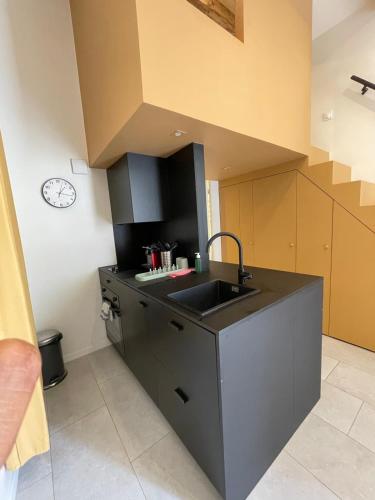 une cuisine avec un évier et une horloge murale dans l'établissement Joli studio, à Marseille