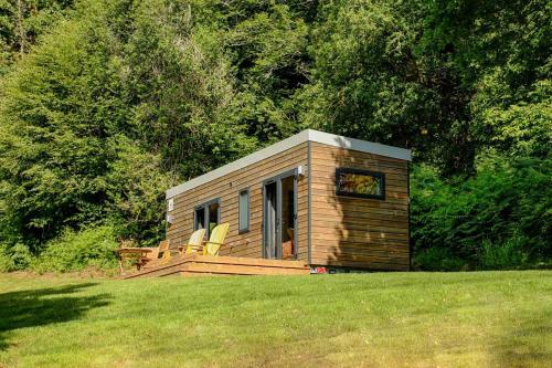 a small cabin with two chairs on a grass field at FORET TOTEM - Hébergements nature et bien-être en pleine forêt in Persquen