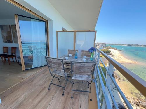 a balcony with a table and chairs on the beach at Soleil couchant in Roscoff