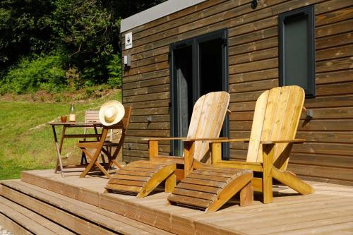two chairs and a table on a deck with a cabin at FORET TOTEM - Hébergements nature et bien-être en pleine forêt in Persquen