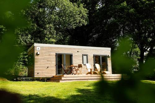 a small cabin with two chairs and a table at FORET TOTEM - Hébergements nature et bien-être en pleine forêt in Persquen