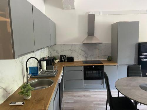 a kitchen with white cabinets and a sink and a table at AUDRU APARTMENT Near Audru Golf and Valgeranna beach in Audru