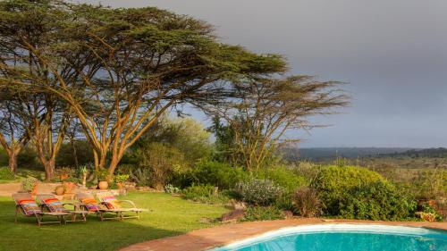 a group of chairs and a table next to a pool at Ololo Safari Lodge & Farm in Nairobi
