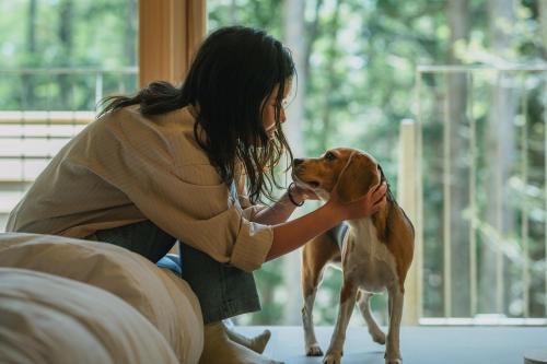 a woman petting a dog in a room at SANU 2nd Home 那須1st in Nasu