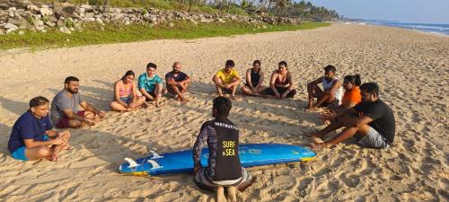 a group of people sitting in the sand on a beach at The Hostel Stories, Varkala - Helipad Road in Varkala