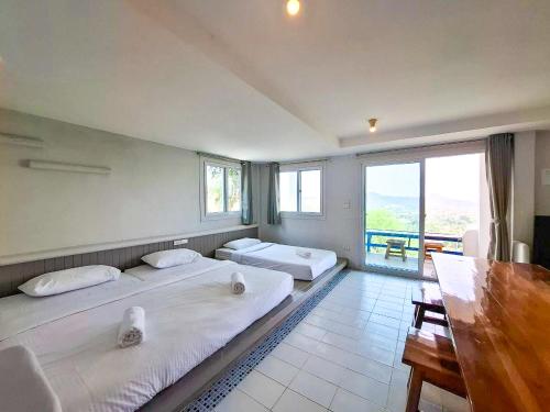 two beds in a room with a large window at Tawanja Resort in Ban Mai