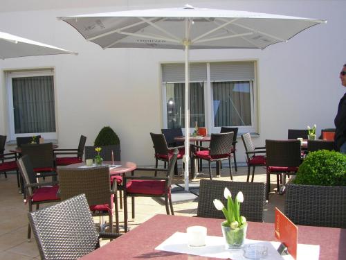 a patio with tables and chairs and an umbrella at Hotel Amadis in Harsewinkel