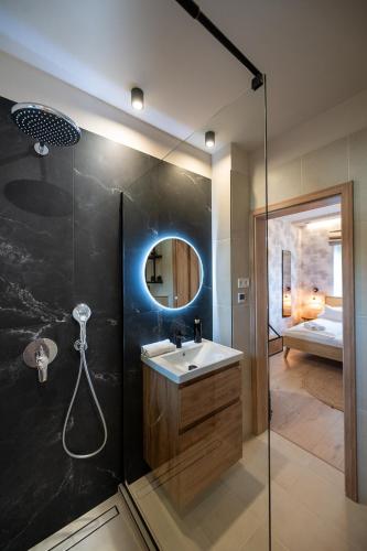 a bathroom with a sink and a shower with a mirror at BoKe Prémium Apartmanok in Szarvas