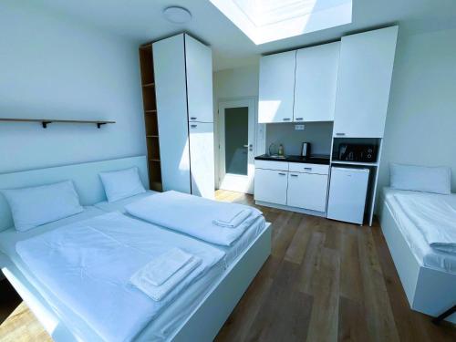 a white bedroom with a large bed and a kitchen at Bella Apartments Brno in Brno