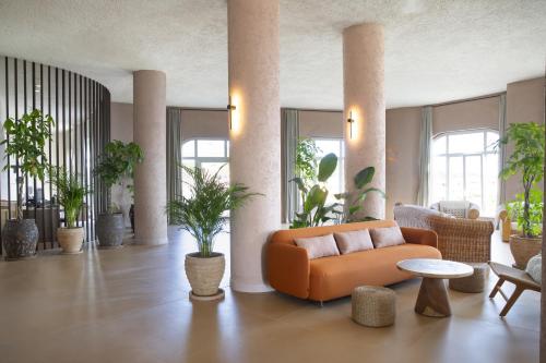 a living room with an orange couch and plants at Mangia's Sardinia Resort - NEW OPENING in Santa Teresa Gallura