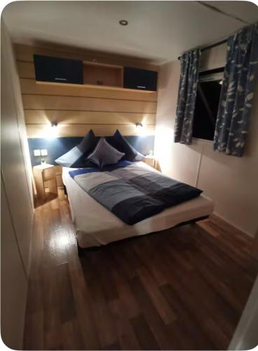 a bedroom with a large bed with blue pillows at Mobile-Home near to Europa Park, Rulantica in Boofzheim